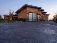 a large wooden home with driveway leading up to the garage entrance at sunset with blue skies