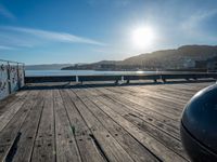 the sun is setting on a clear, bright sky above water and a wooden deck