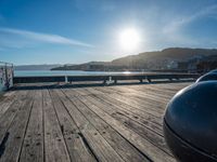 the sun is setting on a clear, bright sky above water and a wooden deck