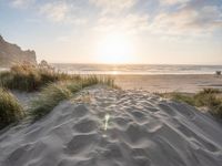 the sun is shining down over the sand dunes on the beach while the water gently rushes the shore