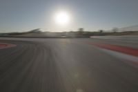 a blurry image shows a sun shining brightly over an empty track on a clear day