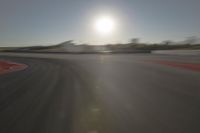 a blurry image shows a sun shining brightly over an empty track on a clear day