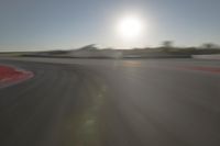 a blurry image shows a sun shining brightly over an empty track on a clear day