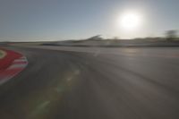 a blurry image shows a sun shining brightly over an empty track on a clear day