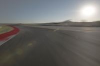 a blurry image shows a sun shining brightly over an empty track on a clear day