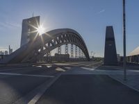 the sun shines over a city street bridge with a curved walkway that runs across