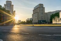 the sun is shining over a street and water feature fountain in the background of a big building