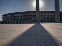 the sun shining through a large building with an olympic symbol on it's side