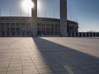 the sun shining through a large building with an olympic symbol on it's side