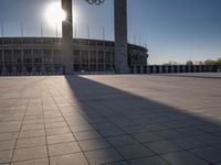 the sun shining through a large building with an olympic symbol on it's side