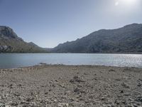 a red fire hydrant sits at the edge of a lake in the mountains of a desert