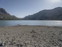 a red fire hydrant sits at the edge of a lake in the mountains of a desert