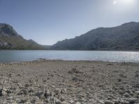 a red fire hydrant sits at the edge of a lake in the mountains of a desert