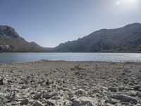 a red fire hydrant sits at the edge of a lake in the mountains of a desert