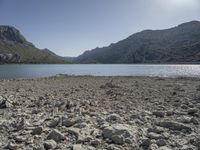 a red fire hydrant sits at the edge of a lake in the mountains of a desert