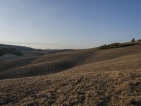 an image of a beautiful day in the hills with no clouds in the sky while someone has fallen grass and walks