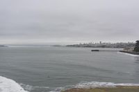 a lone surfer takes off for the waves to pass by a jetty out to sea