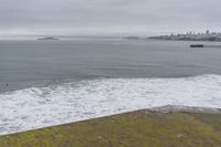a lone surfer takes off for the waves to pass by a jetty out to sea