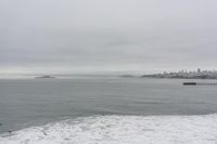 a lone surfer takes off for the waves to pass by a jetty out to sea