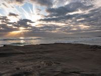 there is a surfer that is walking across the rocks under a stormy sky at sunset