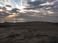 there is a surfer that is walking across the rocks under a stormy sky at sunset