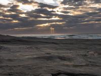 there is a surfer that is walking across the rocks under a stormy sky at sunset