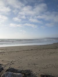 two surfers are on the beach in the sand near the water with waves coming up