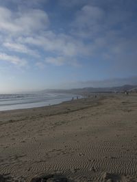 two surfers are on the beach in the sand near the water with waves coming up