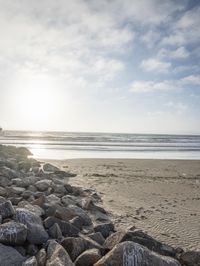 two surfers are on the beach in the sand near the water with waves coming up