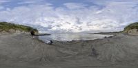 a surreal view of a beach with rocks and ocean below with sun shining through the clouds