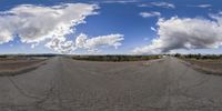 a fish eye view of a road going into the sky with clouds in the background