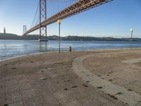 a large suspension bridge spanning the width of a body of water with a light on top and a few steps going up