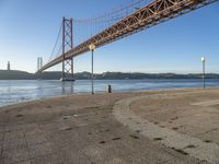 a large suspension bridge spanning the width of a body of water with a light on top and a few steps going up