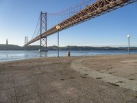 a large suspension bridge spanning the width of a body of water with a light on top and a few steps going up