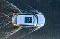 an suv driving through water at high speeds in the ocean with its top view open