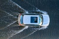 an suv driving through water at high speeds in the ocean with its top view open