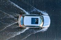 an suv driving through water at high speeds in the ocean with its top view open