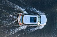 an suv driving through water at high speeds in the ocean with its top view open