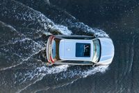 an suv driving through water at high speeds in the ocean with its top view open