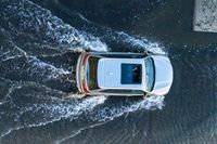 an suv driving through water at high speeds in the ocean with its top view open