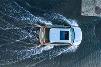 an suv driving through water at high speeds in the ocean with its top view open