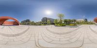 a fisheye lens of a building in the foreground and on the right, a bench, and a park