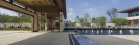 fountains at the entrance of an outdoor building with trees in background and large patio area