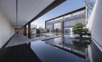 a glass walkway leads to an office building by the water feature in the pool of the building