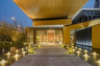 this is a long walkway with lit up water features in a lobby area that leads into a glassy building