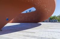 a view of a modern architecture made from bricks and concretes in a plaza on the waterfront, with a man standing