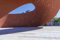 a view of a modern architecture made from bricks and concretes in a plaza on the waterfront, with a man standing