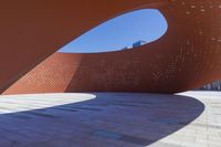 a view of a modern architecture made from bricks and concretes in a plaza on the waterfront, with a man standing