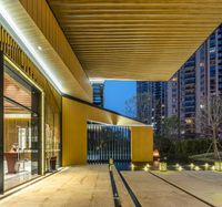 large buildings with wooden roof are seen through an open walkway in front of the building