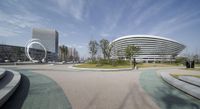 the circular landscaped park on top of a hill is pictured by two modern buildings